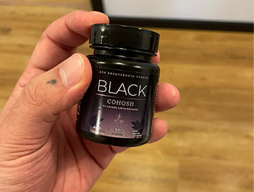 Пузырек препарата Black Cohosh в мужской руке.