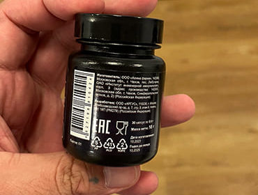 Бутылочка с Black Cohosh в мужской руке крупным планом.